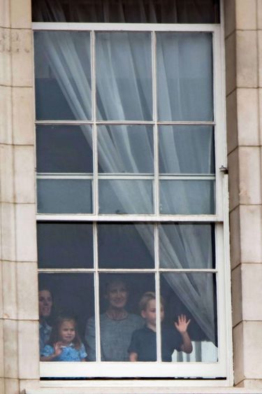 Księżniczka Charlotte i książę George stroją miny w oknie Pałacu Buckingham