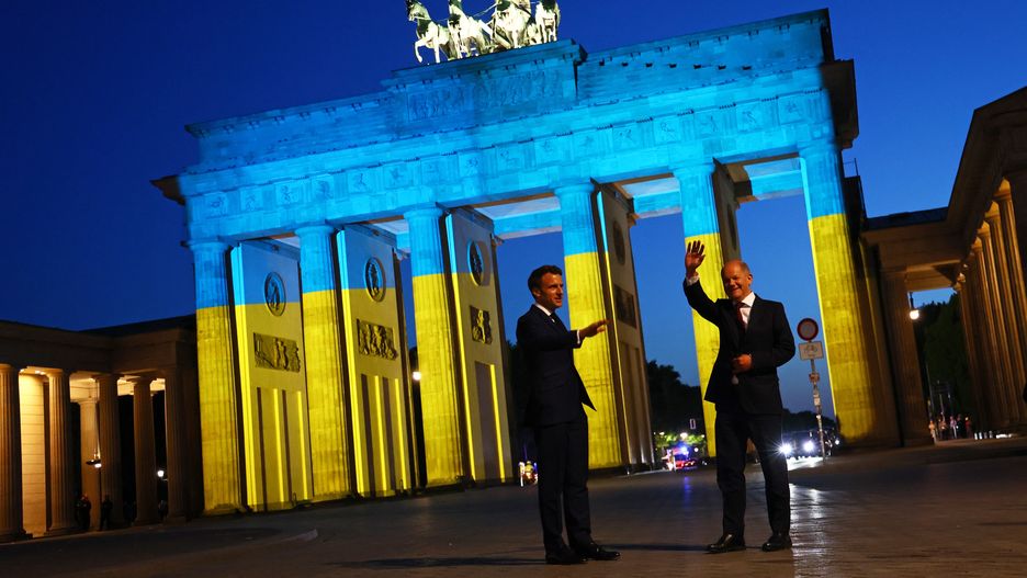 French President Emmanuel Macron (L) and German Chancellor Olaf Scholz visit the Brandenburg Gate enlightened with the colours of the Ukrainian flag in Berlin, Germany on May 9, 2022. (Photo by Emmanuele Contini/NurPhoto via Getty Images)