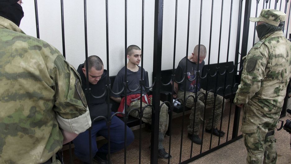 Trzej zagraniczni ?o?nierze skazani na ?mier? za walk? po stronie Ukrainy
Two British citizens Aiden Aslin, left, and Shaun Pinner, right, and Moroccan Saaudun Brahim, center, sit behind bars in a courtroom in Donetsk, in the territory which is under the Government of the Donetsk People's Republic control, eastern Ukraine, Thursday, June 9, 2022. The two British citizens and a Moroccan have been sentenced to death by pro-Moscow rebels in eastern Ukraine for fighting on Ukraine's side. The three men fought alongside Ukrainian troops and surrendered to Russian forces weeks ago. (AP Photo)
AP