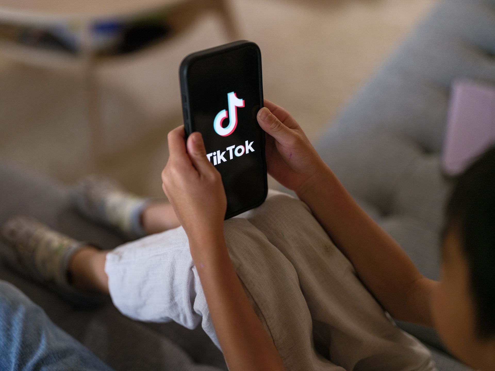 SYDNEY, AUSTRALIA - DECEMBER 07: A 7-year-old teenage boy looks at a phone screen with TikTok logo is displayed on December 07, 2025 in Sydney, Australia. The Online Safety Amendment (Social Media Minimum Age) Act 2024 requires social media platforms, including TikTok, Instagram, Facebook, YouTube, Snapchat, X, Reddit, Threads, Twitch, and Kick to implement age-verification systems and take reasonable steps to prevent account creation by users under 16, with non-compliant platforms facing penalties of up to A$50 million. (Photo by George Chan/Getty Images)