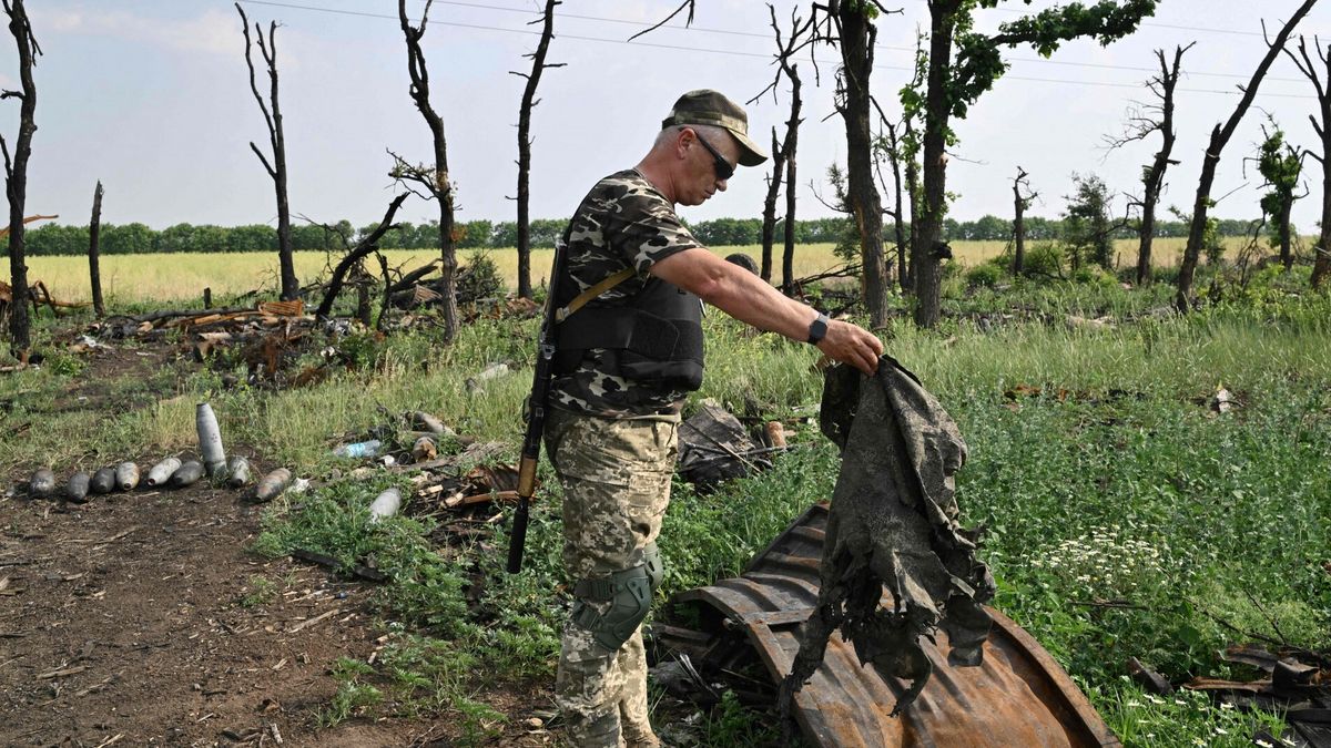 Ukraiński żołnierz przegląda gruzy obok zniszczonych rosyjskich pojazdów wojskowych na polu niedaleko miasta Mikołajów