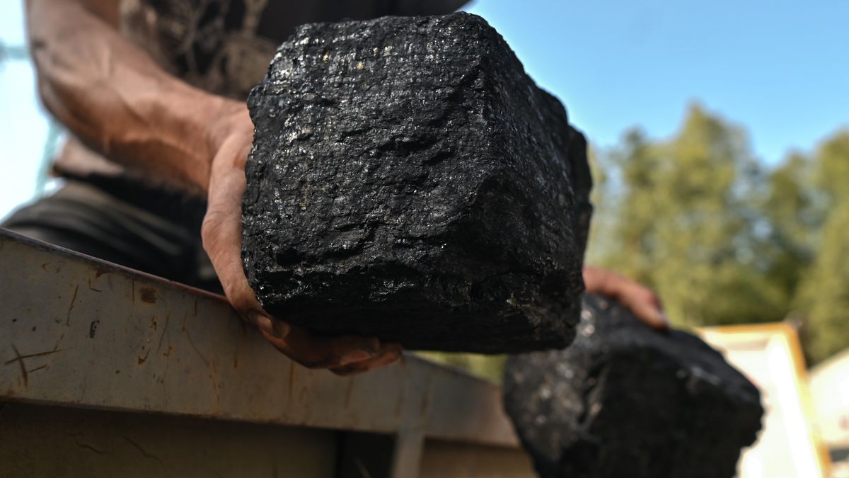 LIBIAZ, POLAND - SEPTEMBER 08: A man is holding two large coals on a trailer of a car parked in front of the Janina coal mine, a large mine in the south of Poland. The energy crisis is slowly heating up in Poland. The lack of coal in the Polish market is due to the decarbonization process: when domestic production was reduced and the market needs were supplemented with imports from Russia, which, following the introduction of the embargo on Russian coal, resulted in an 8 million tonne deficit causing coal shortages and price rises. Customers can buy coal directly from the mine, but must must subscribe to a waiting list and will be called upon to pick up the coal after a couple of weeks. The limit is three tonnes per buyer, with his own transport. Buyers wait in line for up to several days to complete the formalities, but many are attracted by the price: PLN 1,450 per ton of coal compaired to PLN 3,200-3,800 in warehouses. (Photo by Artur Widak/Anadolu Agency via Getty Images)
