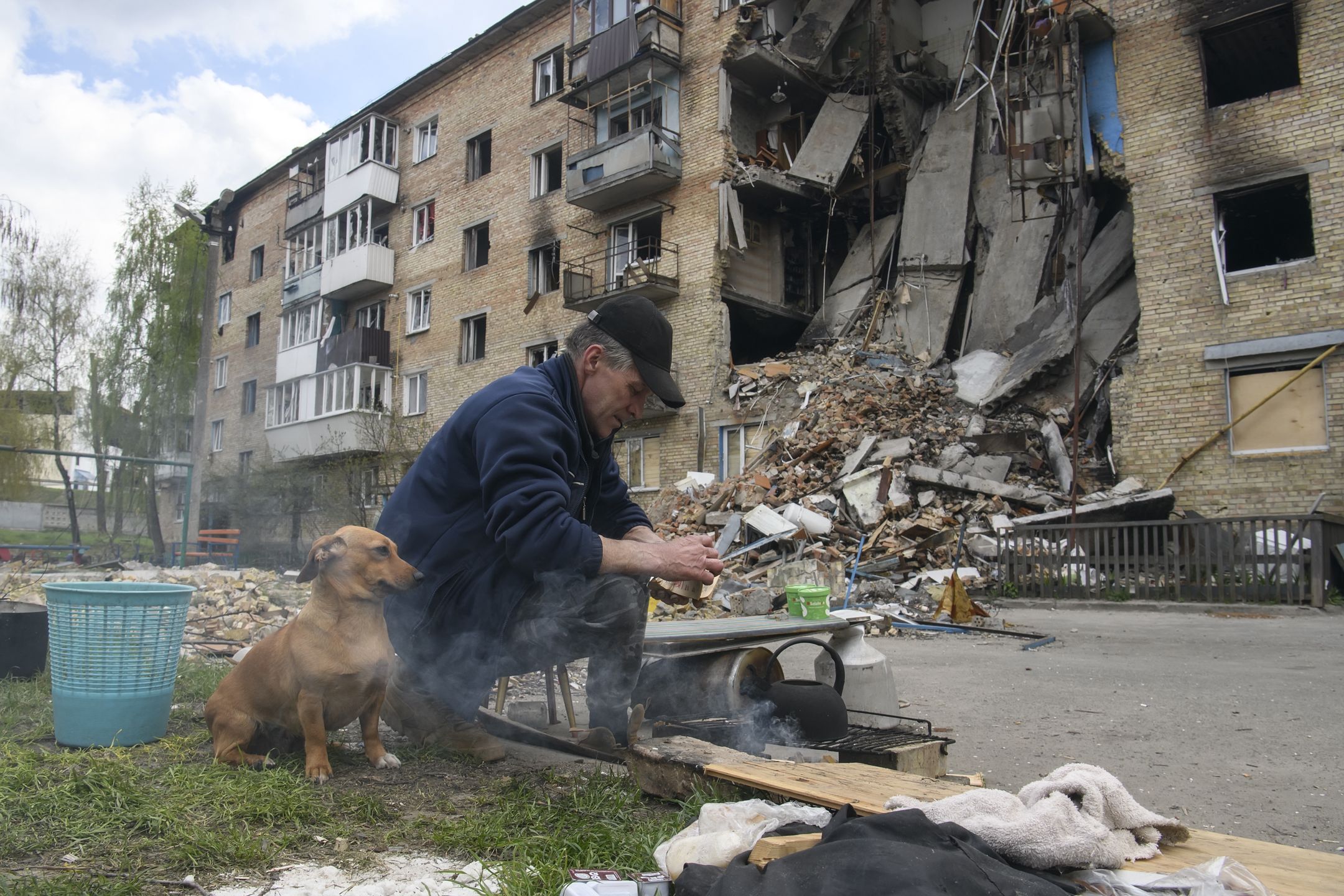 Local man warms water on the fire close to a residential building destroyed during Russia's invasion of Ukraine in Hostomel, Ukraine April 29, 2022. (Photo by Maxym Marusenko/NurPhoto via Getty Images)