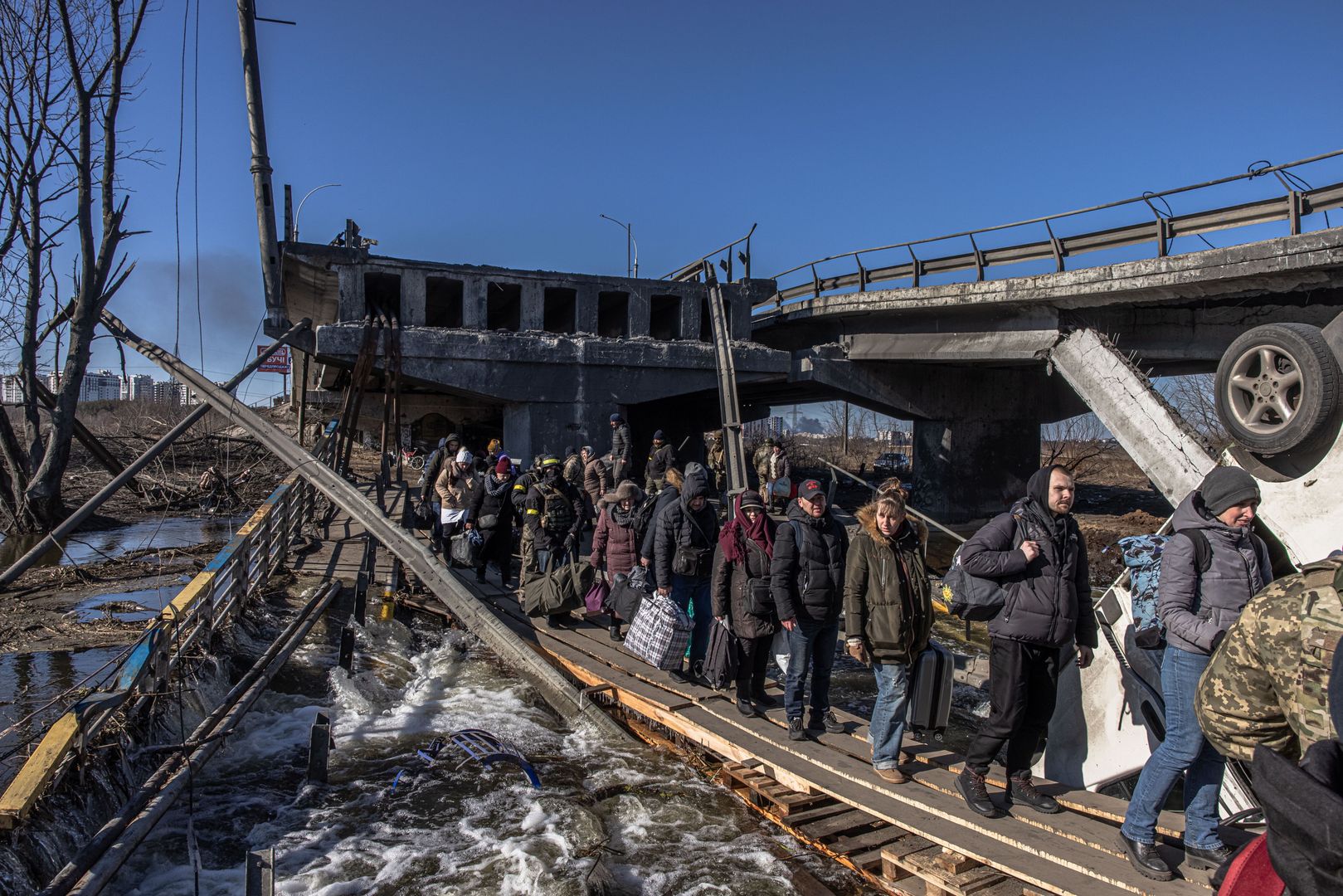  epa09815823 Residents with their luggage cross a destroyed bridge as they flee from the frontline town of Irpin, Kyiv (Kiev) region, Ukraine, 10 March 2022. Thousands of residents are feeling Irpin and Bucha, as well as other settlements near Kyiv which were the most affected by the Russian army invasion.  EPA/ROMAN PILIPEY Dostawca: PAP/EPA.