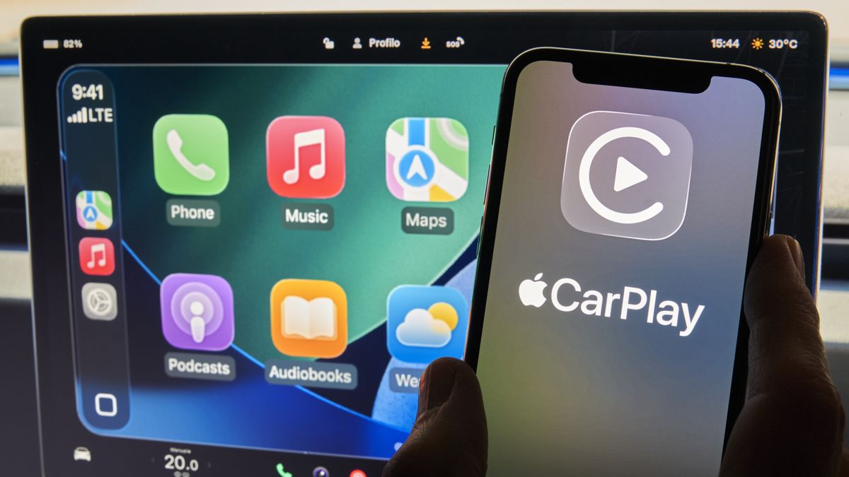 An iPhone showing Apple CarPlay is seen in front of a Tesla Model 3 screen displaying a CarPlay-style interface in Bari, Italy, on November 15, 2025. (Photo by Matteo Della Torre/NurPhoto via Getty Images)