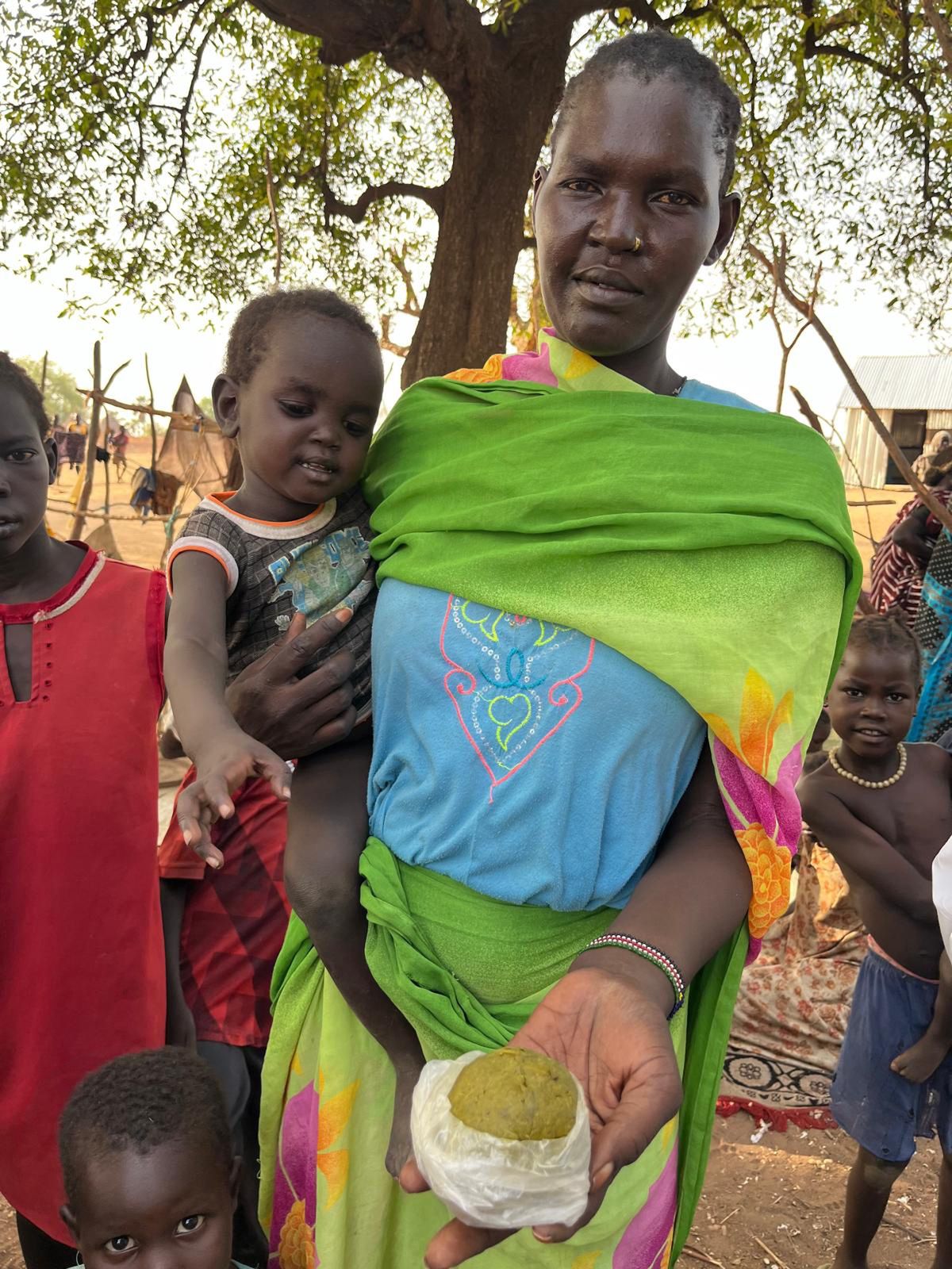 A woman shows a paste made from leaves. In South Sudan, there is a shortage of food, forcing people to eat this kind of sustenance.