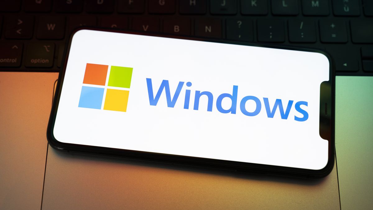The Windows logo appears on the screen of a smartphone placed on a computer keyboard illuminated by orange and green light. Microsoft releases a major update to Windows 11 (25H2), and Windows 10 support ends permanently on October 14. In Creteil, France, on October 9, 2025. (Photo by Samuel Boivin/NurPhoto via Getty Images)