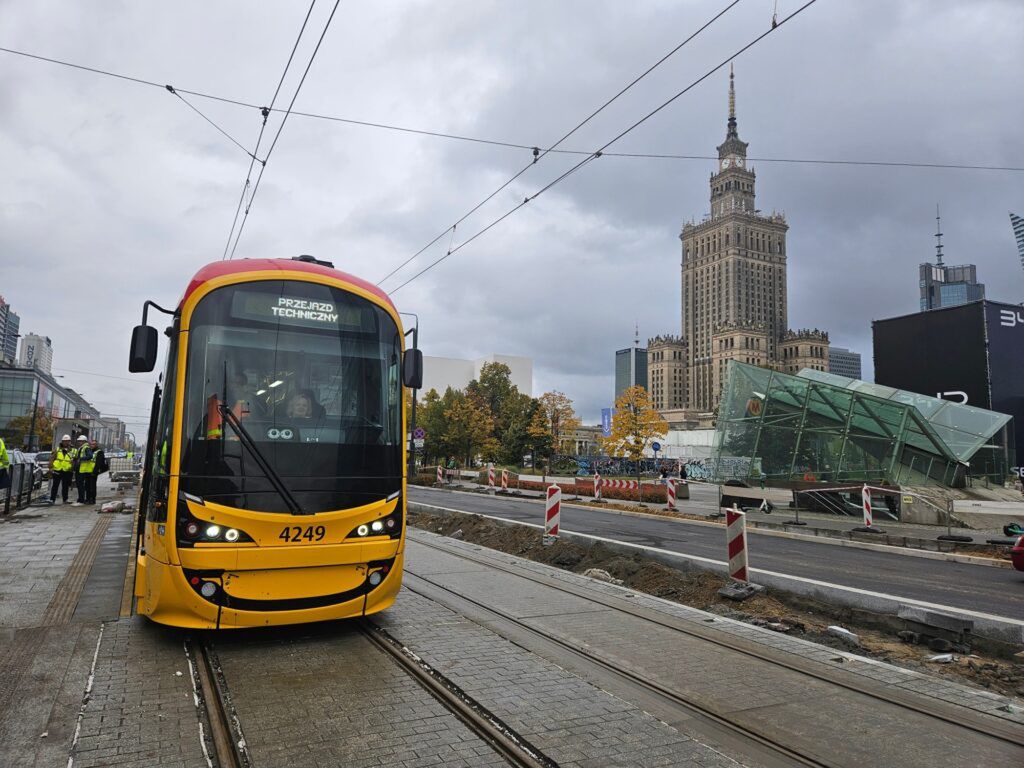 Tramwaj z numerem 4249 przejeżdża przez plac budowy w mieście, w tle widoczny Pałac Kultury i Nauki.