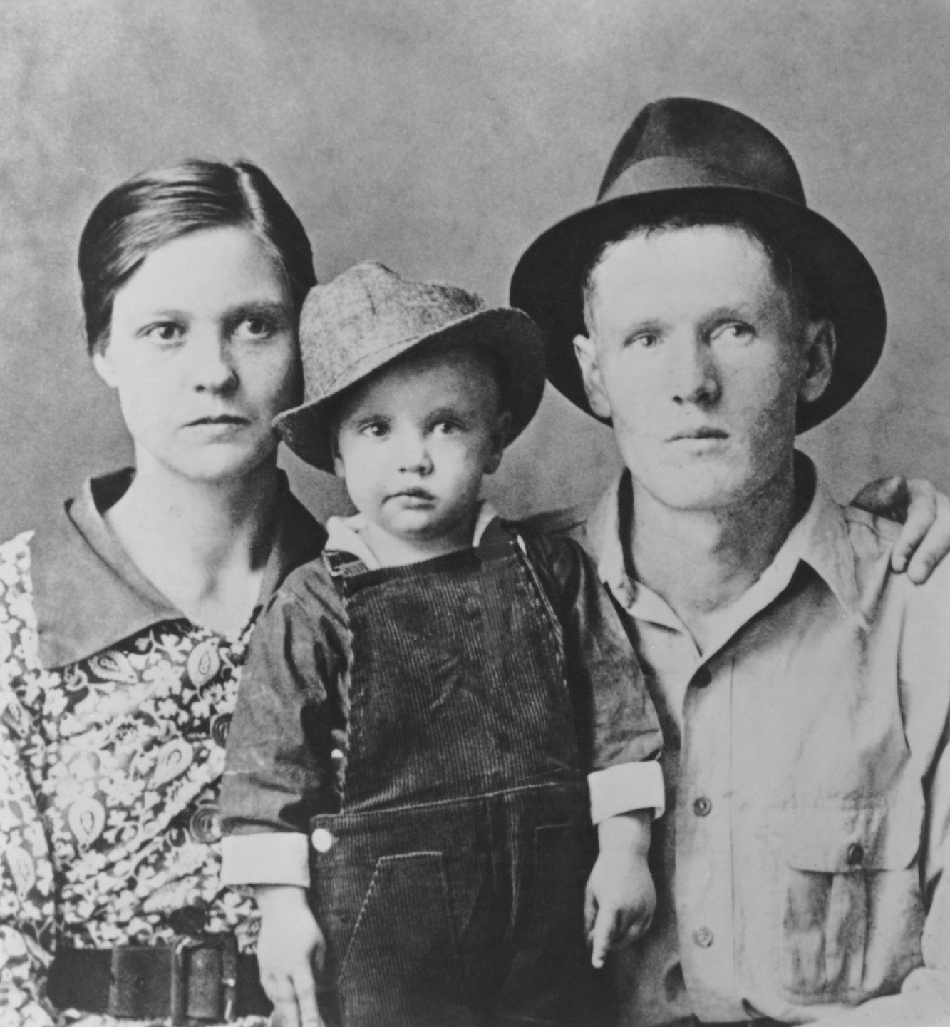Elvis Presley With His ParentsTUPELO, MI - 1937:  Two year old Elvis Presley poses for a family portrait with his parents Vernon Presley and Gladys Presley in 1937 in Tupelo, Mississippi. (Photo by Michael Ochs Archive/Getty Images)Michael Ochs ArchivesCasual Wear, Clothing, Rock, Rock And Roll, Utility Pants, Dungarees, Brimmed Hat, Family, DCR044903, Accessory, Casually Dressed, Headgear, Casualwear, Headwear, Overalls, Bibbed Pants, Hat, Accessories, Trilby, Hats, Three People, Work Pants, Fedora, Coveralls
