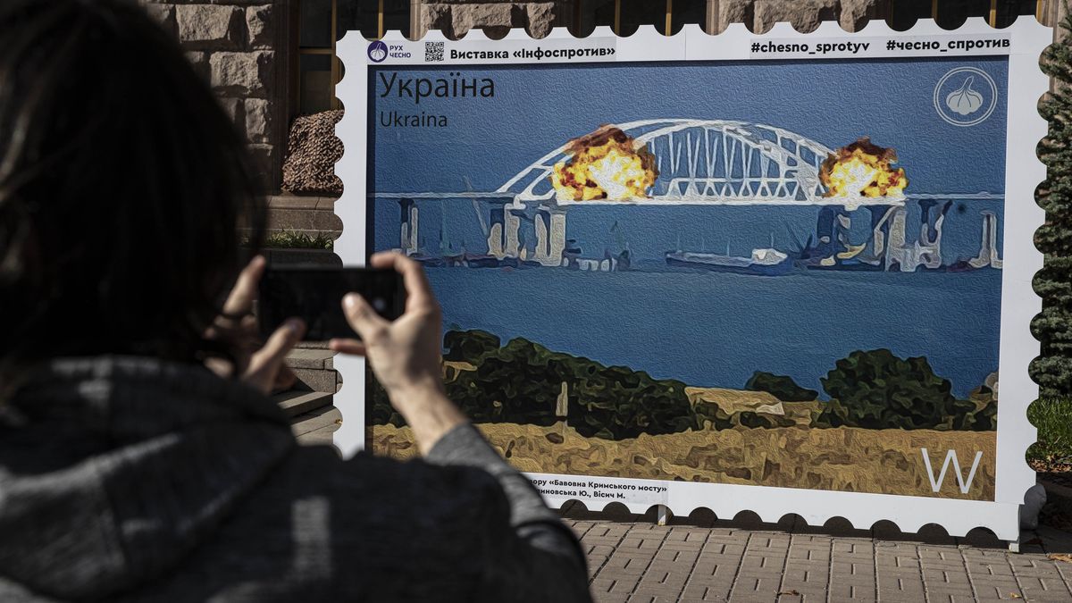 KYIV, UKRAINE - OCTOBER 12: People take photos in front of an image of a stamp showing explosions on the Kerch Bridge, a key supply route Russia built after it illegally annexed Crimea, on October 12, 2022 in Kyiv, Ukraine. (Photo by Metin Aktas/Anadolu Agency via Getty Images)