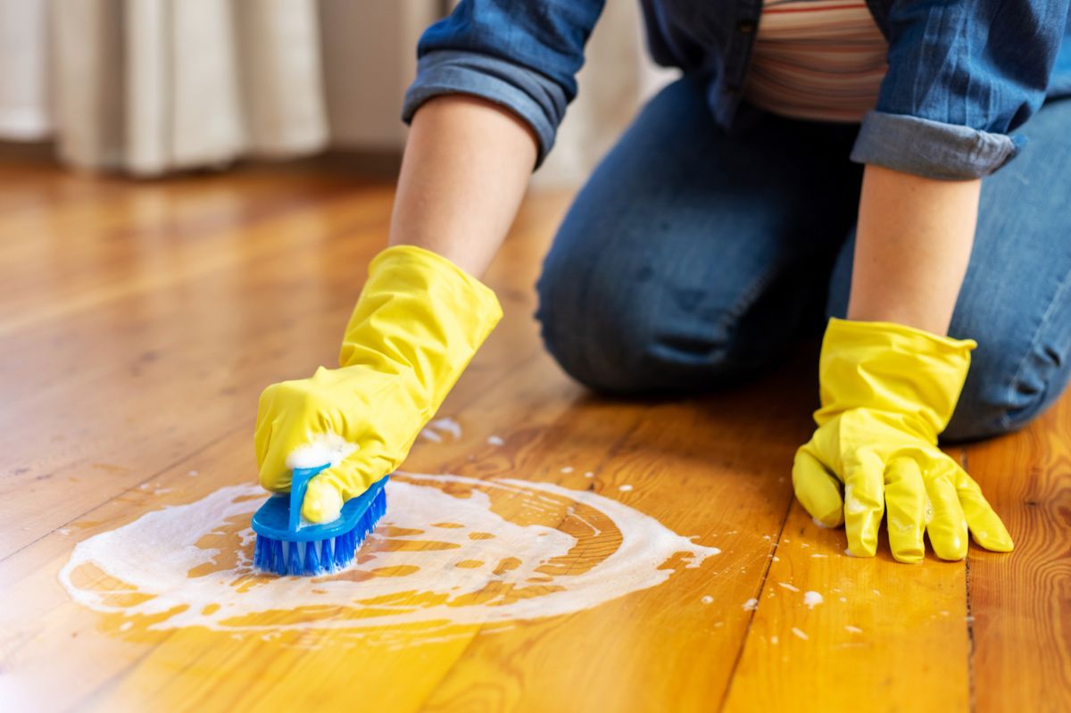 The woman is scrubbing the floor on her knees.