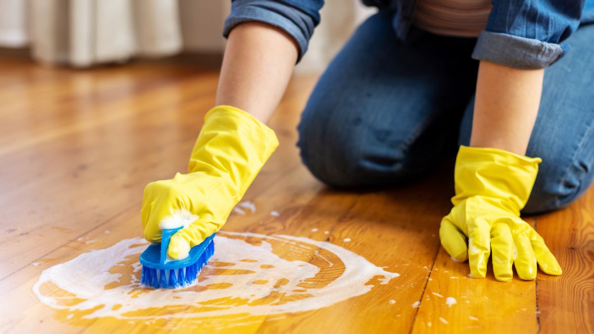 Kobieta szoruje podłogę na kolanach