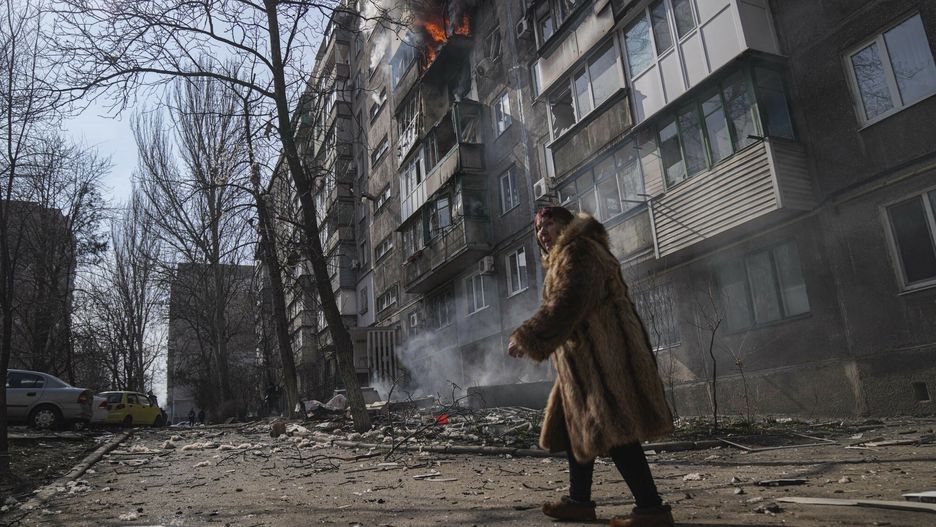 TemporaryA woman walks past a burning apartment building after shelling in Mariupol, Ukraine, Sunday, March 13, 2022. (AP Photo/Evgeniy Maloletka)AP
