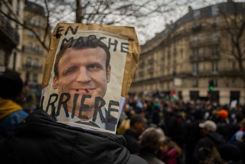 A protestor holds a placard featuring an image of French President Emmanuel Macron during a demonstration against pension reform on Boulevard Voltaire in central Paris, France, on Tuesday, March 28, 2023. French unions are holding a new day of nationwide strikes Tuesday to try to force President Emmanuel Macron to reverse his decision to push through unpopular pension reforms. Photographer: Nathan Laine/Bloomberg via Getty Images