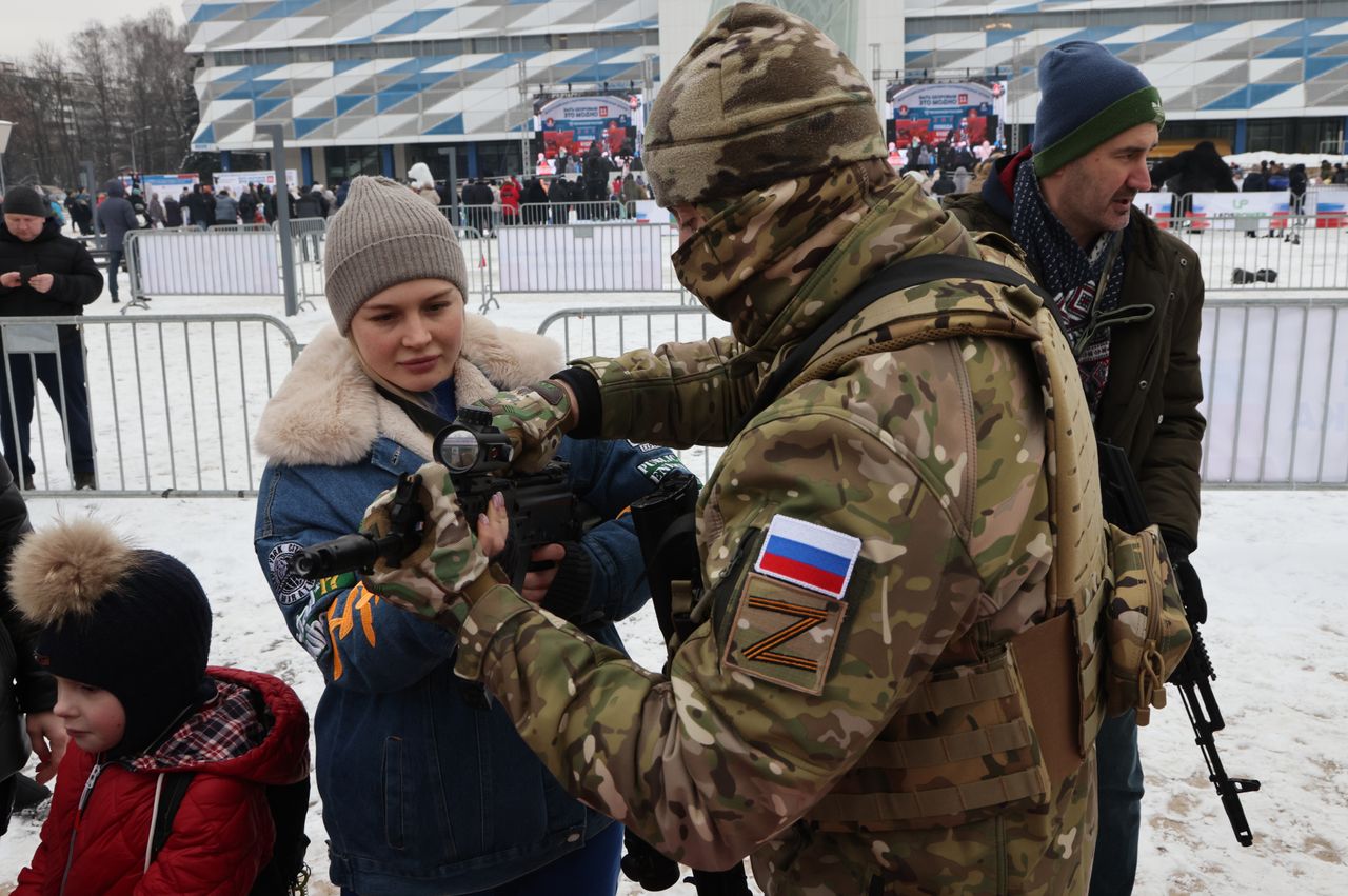 Piknik patriotyczno-wojskowy w Krasnogorsku. Oficer FSB tłumaczy kobiecie z dzieckiem, jak obsługiwać karabin AK-47 