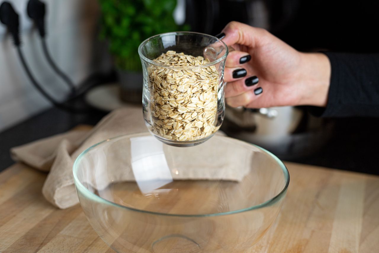 Oatmeal being poured from a glass into a glass bowl