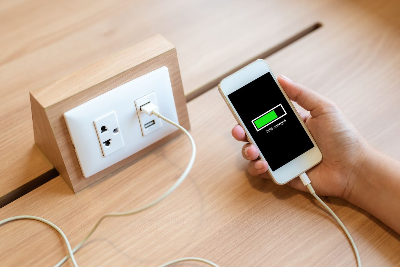 Woman's hand holding smart phone and charging battery from built in usb socket on the table
Weerapat Wattanapichayakul
