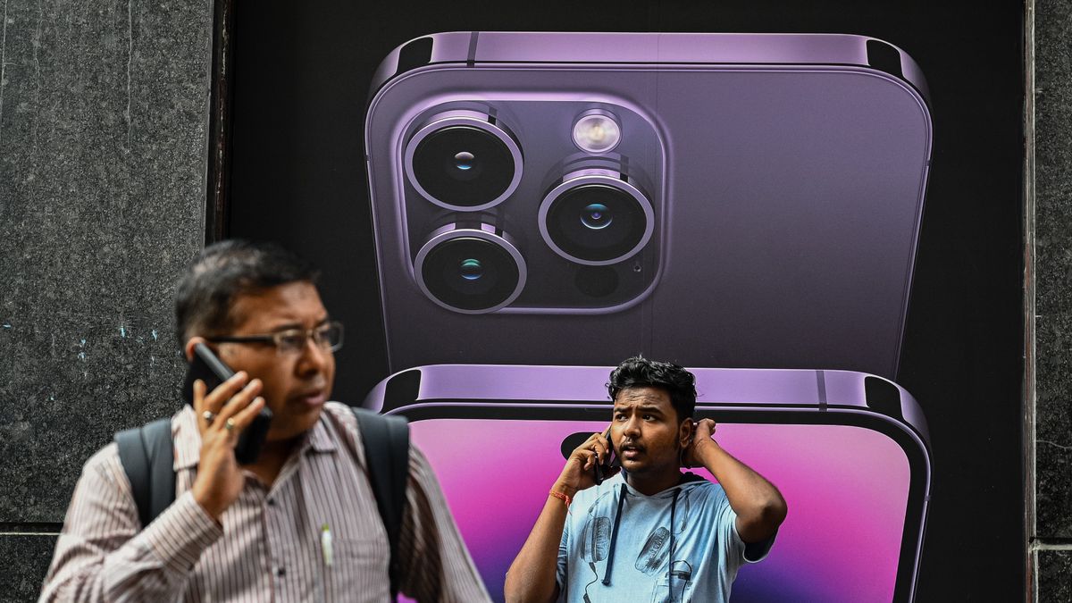 Men talk on their mobile phones in front of an iphone 14 advertisement, in Kolkata on September 27, 2022. Apple Inc. said on Monday it will manufacture its latest iPhone 14 in India, according to media reports.  (Photo by Sankhadeep Banerjee/NurPhoto via Getty Images)