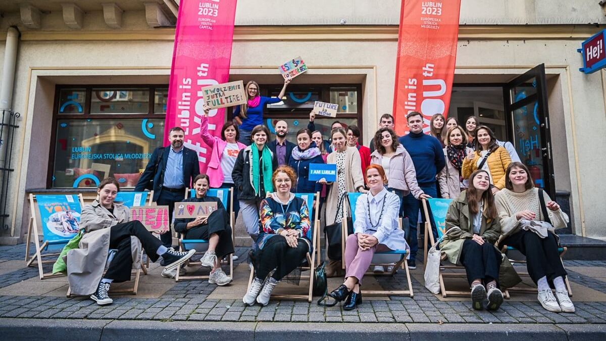Grupa ludzi przed "HEJ"