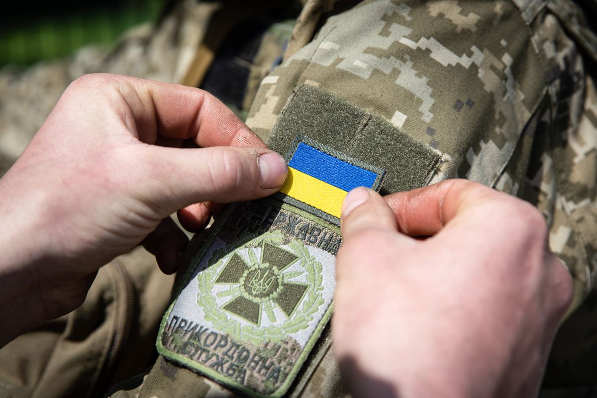 STANTSIYA MEREFA, KHARKIV, UKRAINE - 2022/04/25: A Ukrainian soldier sticks a Ukraine national flag badge to his comrade's arm during his patrol in an undisclosed location in Kharkiv oblast. As the Ukraine-Russian war rages for over two months, Russia now shifted its tactical aim to the eastern part of Ukraine, and now has concentrated the offensive on the eastern part of the country. Kharkiv oblast is now under constant threat of Russian bombardment and airstrikes. Russia invaded Ukraine on 24 February 2022, triggering the largest military attack in Europe since World War II. (Photo by Alex Chan Tsz Yuk/SOPA Images/LightRocket via Getty Images)