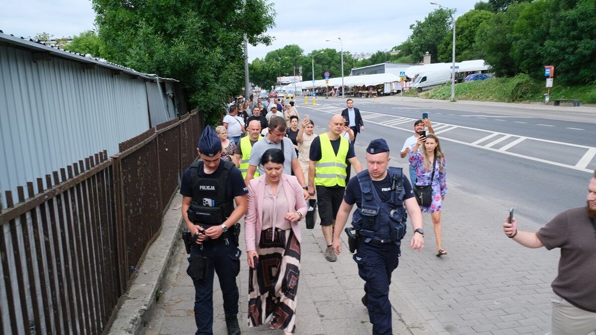 Prezes Lubelskich Dworców Anna Kusiak w asyście policji i idący za nimi handlarze z targowiska przy ul. Ruskiej