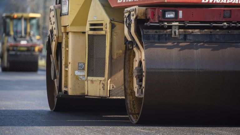 Walec drogowy marki Dynapac pracuje na nowo wyłożonej nawierzchni asfaltowej.