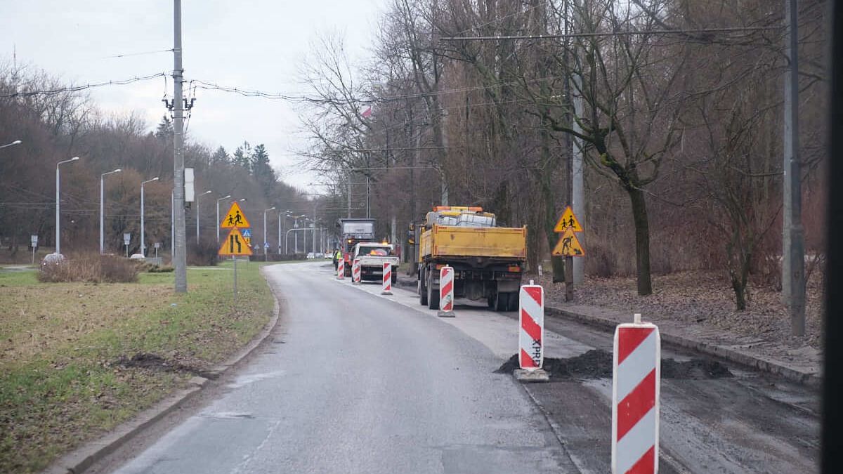 sfrezowany odcinek ulicy głębokiej. w oddali samochód ciężarowy i frezarka drogowa