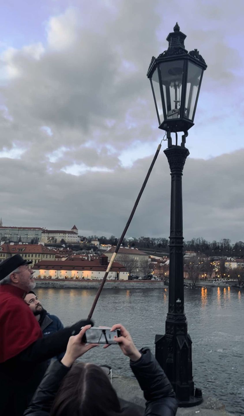 Latarnik zapala latarnie na Moście Karola