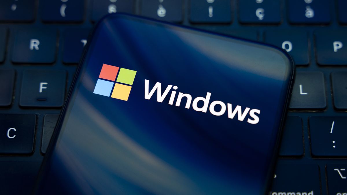 The Windows logo appears on the screen of a smartphone placed on a computer keyboard, which reflects an abstract illustration in blue colors. Microsoft releases a major update to Windows 11 (25H2), and Windows 10 support ends permanently on October 14. In Creteil, France, on October 9, 2025. (Photo by Samuel Boivin/NurPhoto via Getty Images)
