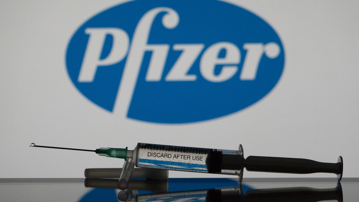 In this photo illustration a covid-19 vaccine is seen with the Pfizer logo in the background. (Photo Illustration by Nikos Pekiaridis/NurPhoto via Getty Images)