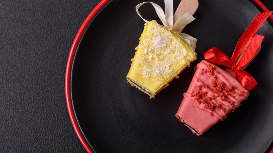 Delicious sweet cheesecake with fruits covered with icing with a wooden stick
