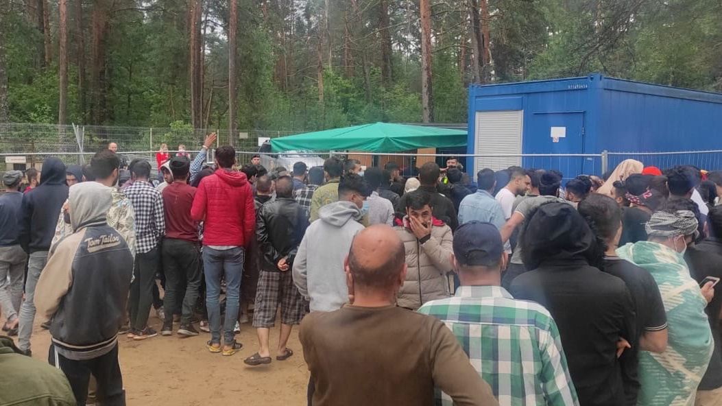 Mężczyźni w obozie w Rudnikach ustawiają się w kolejce do pobrania odcisków palców
