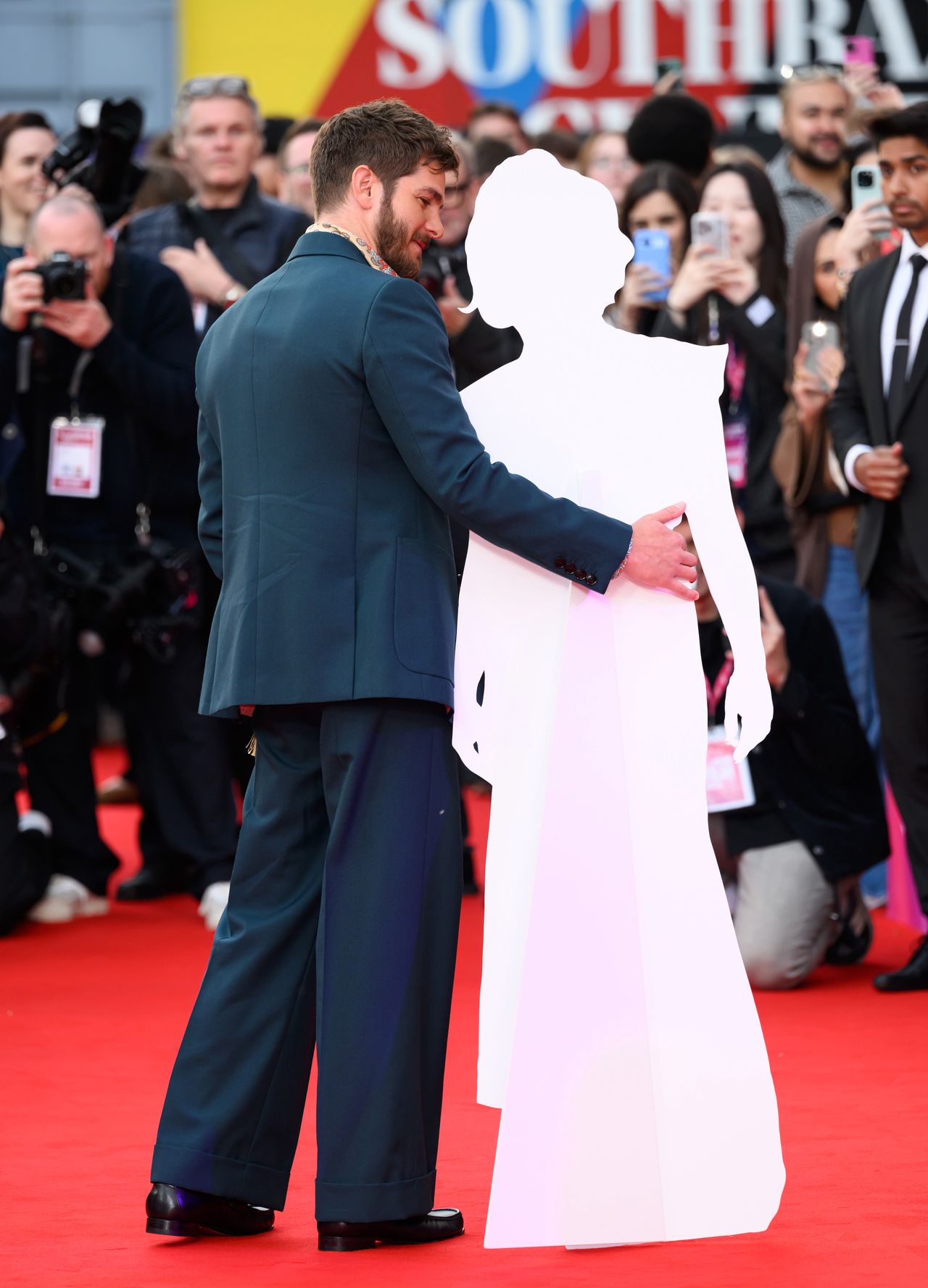 LONDON, ENGLAND - OCTOBER 17: Andrew Garfield poses with a cardboard cutout of Florence Pugh during the "We Live In Time" Headline Gala during the 68th BFI London Film Festival at The Royal Festival Hall on October 17, 2024 in London, England. (Photo by Karwai Tang/WireImage)