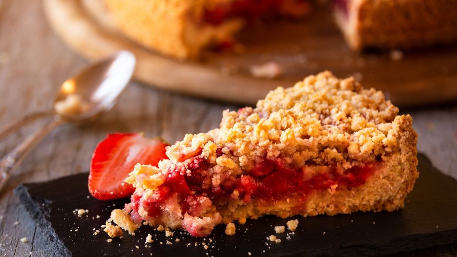 Delicious crumble cake with strawberry on wooden background