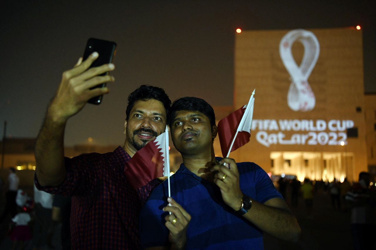 Kibice w Katarze robią sobie selfie przed logiem mistrzostw świata w piłce nożnej, wyświetlonym na ścianie budynku Katarskiego Archiwum Państwowego