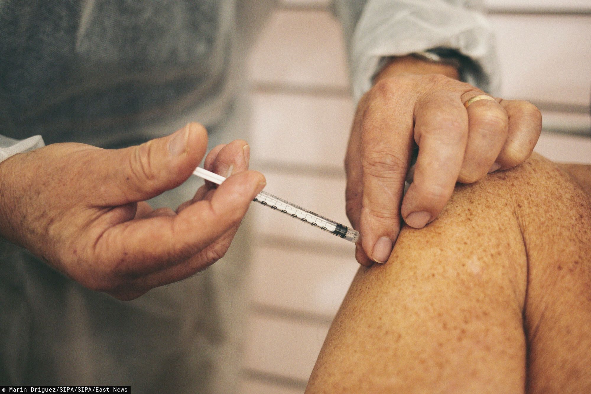 "Podr�?" szczepionki - od fabryki do szczepieniaUn homme recoit le vaccin contre le covid 19  The ultra-secure journey of a vial of the precious Covid-19 vaccine, from the Belgian factory where it was produced to its injection into Colette's arm, in a vaccine park in Indre. His inoculation only lasted three seconds. In the village hall in the Berry village of Villedieu-sur-Indre, the 0.3 milliliter dose is passed into the arm of Colette, a smiling 79-year-old retiree. Produced a few hundred kilometers to the north, in Belgian Flanders, these few drops of Comirnaty, the name of the anti-Covid vaccine developed by Pfizer / BioNTech, have arrived safely, after a real odyssey across Europe. : in small bottles buried under thick layers of dry ice, the dose was transported to France, under escort, with the care that is usually given to the most precious goods.  She crossed the border in a refrigerated truck at -70 ?o C, stopped in one of the "super-refrigerators" with which the French departments were equipped, with instructions to keep their location secret. Then it was thawed in Chateauroux and taken to the cold room of this communal room. A roadtrip that we retraced for a week, step by step, from the bottling to this vaccination in the middle of the French medical desert. //DRIGUEZMARIN_1755.1753/2102181305Marin Driguez/SIPA
