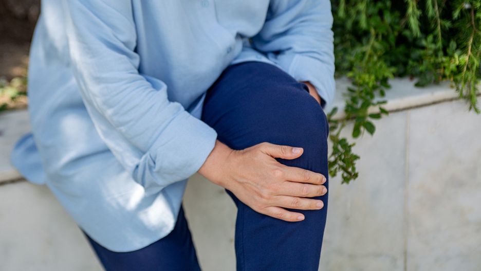 Closeup photography of female hands holding knee. Concept of joint pain.