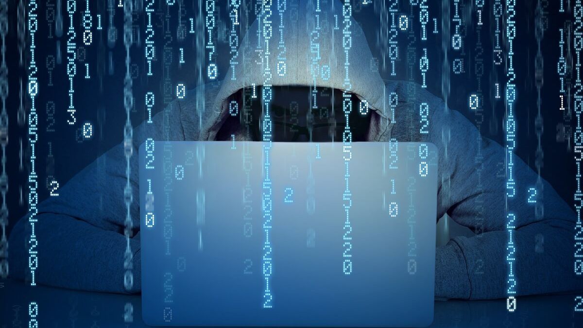 Faceless man hacker working on a laptop on a binary code background