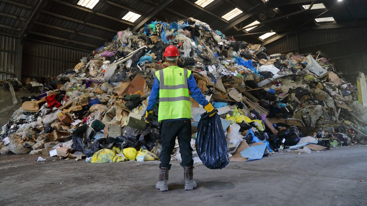 Man holding bag of rubbish at rubbish tip
Peter Cade
refuse, refuse worker, household waste, task