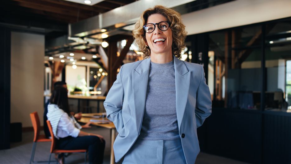 Woman standing in an office, she is smiling and wearing a suitWoman standing in an office, she is smiling and wearing a suit. Business woman working with her colleagues who are having a meeting in the background.business, business people, business person, business woman, caucasian, corporate, employee, entrepreneur, eyeglasses, female, happy, new business, occupation, office, people, person, profession, professional, smile, smiling, standing, woman, work, worker, working, workplace, business, business woman, professional, entrepreneur, office, smile, corporate, person, workplace, profession, people, business people, smiling, work, female, woman, new business, caucasian, eyeglasses, standing, worker, happy, occupation, business person, employee, working