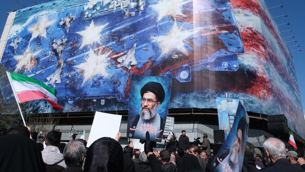 TEHRAN, IRAN - MARCH 1:  People gather in Revolution Square to mourn the assassination of Iran's Supreme Leader who was killed in  joint operation named Epic Fury by Israel and the U.S. in his residence a day before (February 28) on March 1, 2026 in Tehran, Iran. People hold Iranian flags and photos of Ayatollah Khamenei against a huge banner in on the corner of the square depicting an Iranian missile attack on a U.S. carrier stationed in the Persian Gulf. (Photo by Kaveh Kazemi/Getty Images