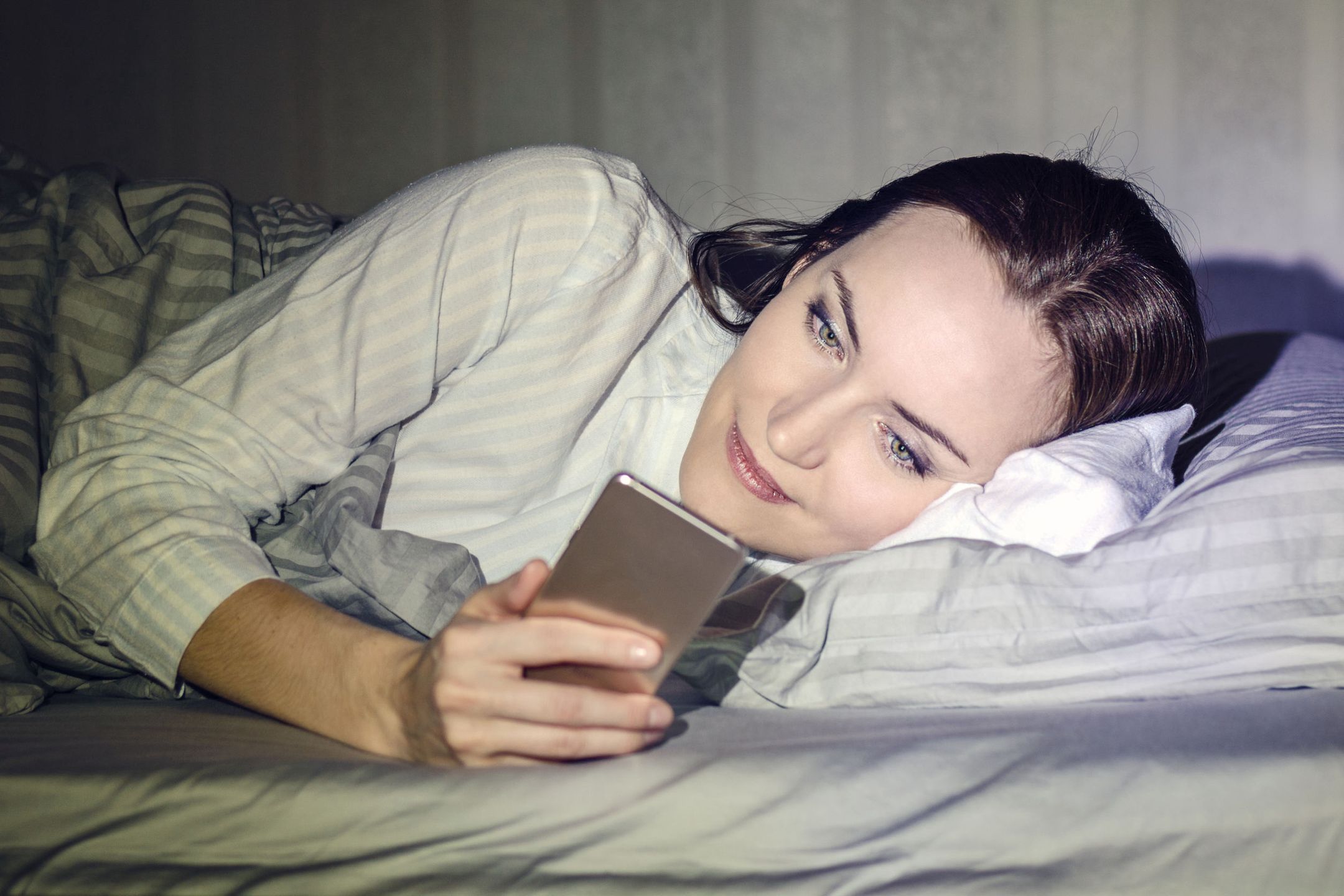 kobieta leżąca w łóżku z telefonem