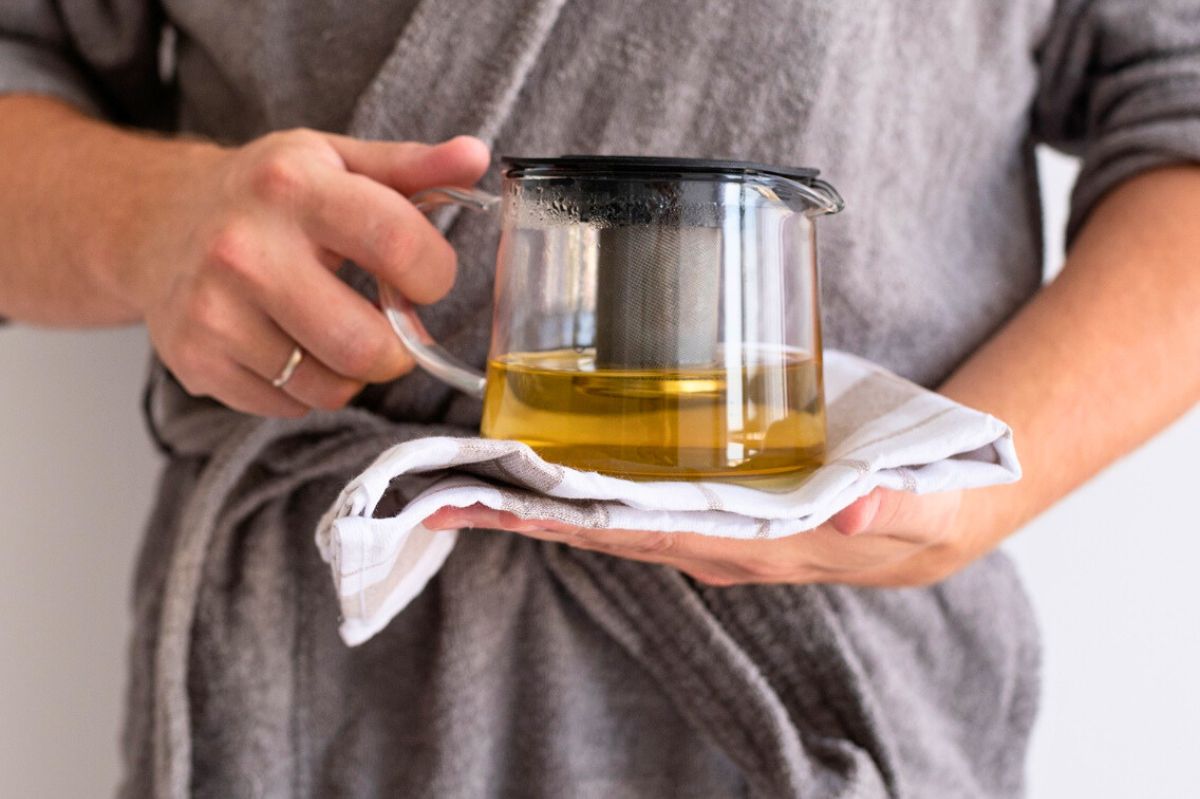 The woman holds a pitcher of infusion in her hands.