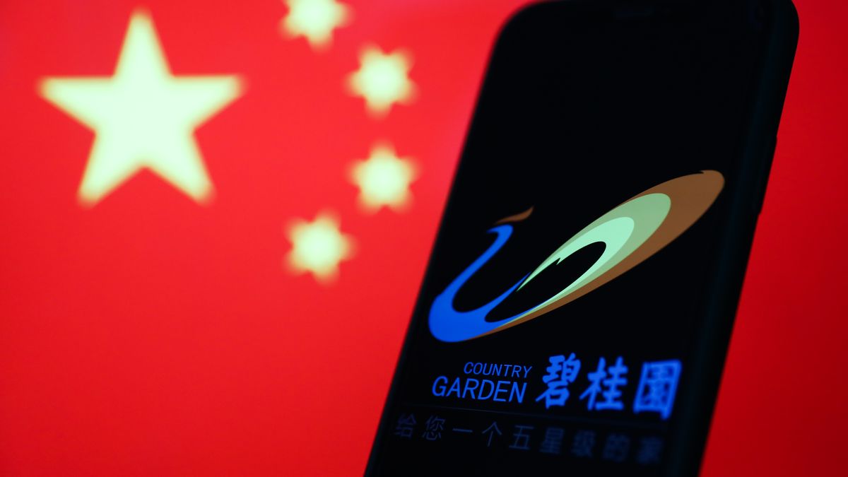 Country Garden logo displayed on a phone screen and Chinese flag displayed on a screen in the background are seen in this illustration photo taken in Krakow, Poland on September 12, 2023. (Photo by Jakub Porzycki/NurPhoto via Getty Images)
