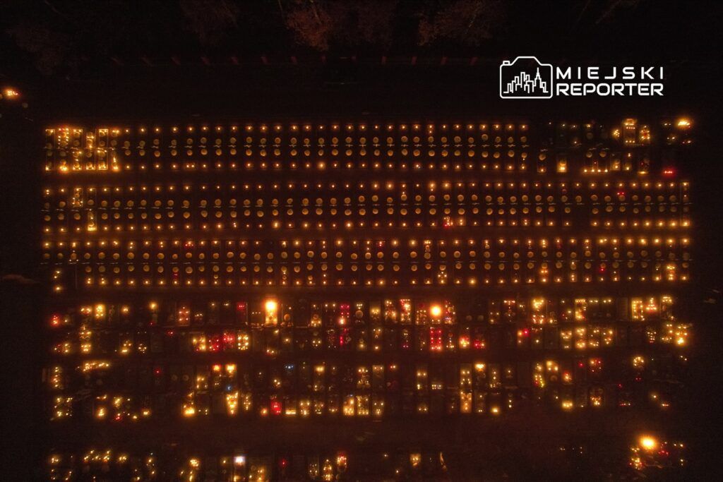 Widok na cmentarz oświetlony setkami zniczy w nocy, tworzący ciepłą, refleksyjną atmosferę.