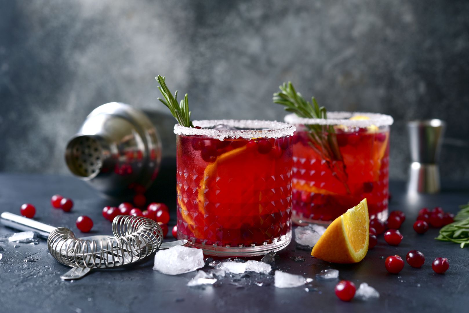 Red christmas cocktail with cranberries and oranges in a glasses on a dark slate, stone or concrete backgroundalcohol, cocktail, mocktail, cranberry, orange, rosemary, christmas, xmas, festive, party, fresh, juice, fruit, berry, soda, fizz, slushie, julep, cooler, water, tonic, daiquiri, margarita, rossini, martini, sangria, wine, aperitif, sparkling, carbonated, drink, beverage, cold, red, syrup, rum, vodka, gin, liquor, recipe, ice, cube, ingredient, food, punch, scotch, lemonade, shaker, winter, black