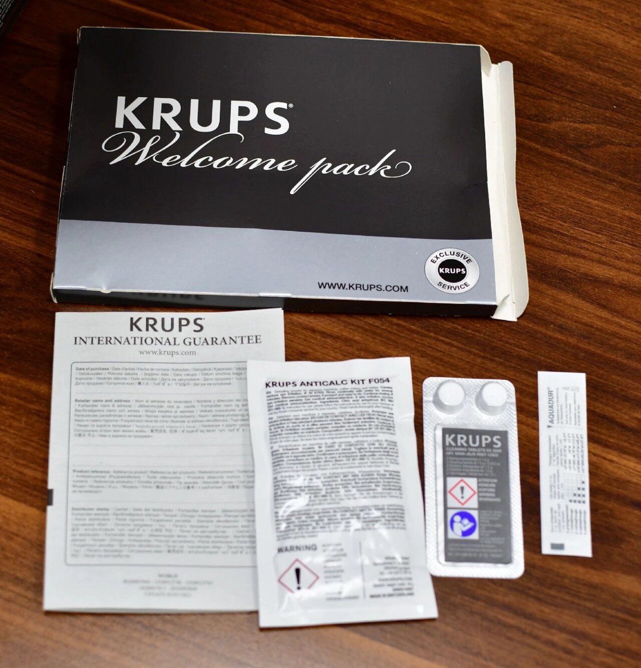 Welcome pack z ekspresu Krups. Znajduje się w nim karta gwarancyjna, odkamieniacz, tabletki czyszczące oraz test twardości wody.