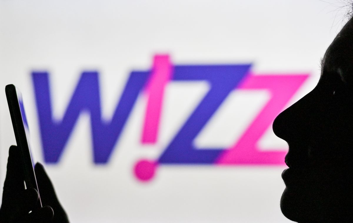 An image of a woman holding a cell phone in front of the Wizz Air logo displayed on a computer screen.
On Tuesday, January 12, 2021, in Edmonton, Alberta, Canada. (Photo by Artur Widak/NurPhoto via Getty Images)