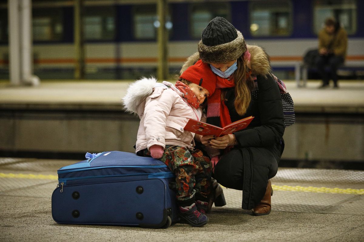 A woman reads a book while holding a child after the arrival of a train with 350 refugees from Kyiv, Ukraine at the Warsaw East train station in Warsaw, Poland on 04 March, 2022. Every day several thousand refugees arrive in Warsaw train stations, fleeing the violence after Russia's invasion. Nearly one million people have fled Ukraine after the Russian invasion and approximately 700 thousand of those have fled to Poland. Thanks to a number of private and public initiatives and the efforts of local municipalities refugees from Ukraine have been received with open arms and enjoy shelter, free food and free transportation in Poland. (Photo by STR/NurPhoto via Getty Images)
