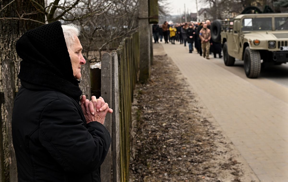 Starychi, Ukraine March 16, 2022:  A resident prays during a funeral procession carrying the casket of two Ukrainain soldiers as it makes its way through the streets of Starychi Wednesday. The men were killed at the International Training Center by a Russian missile in Starychi, Ukraine.(Wally Skalij/Los Angeles Times via Getty Images)